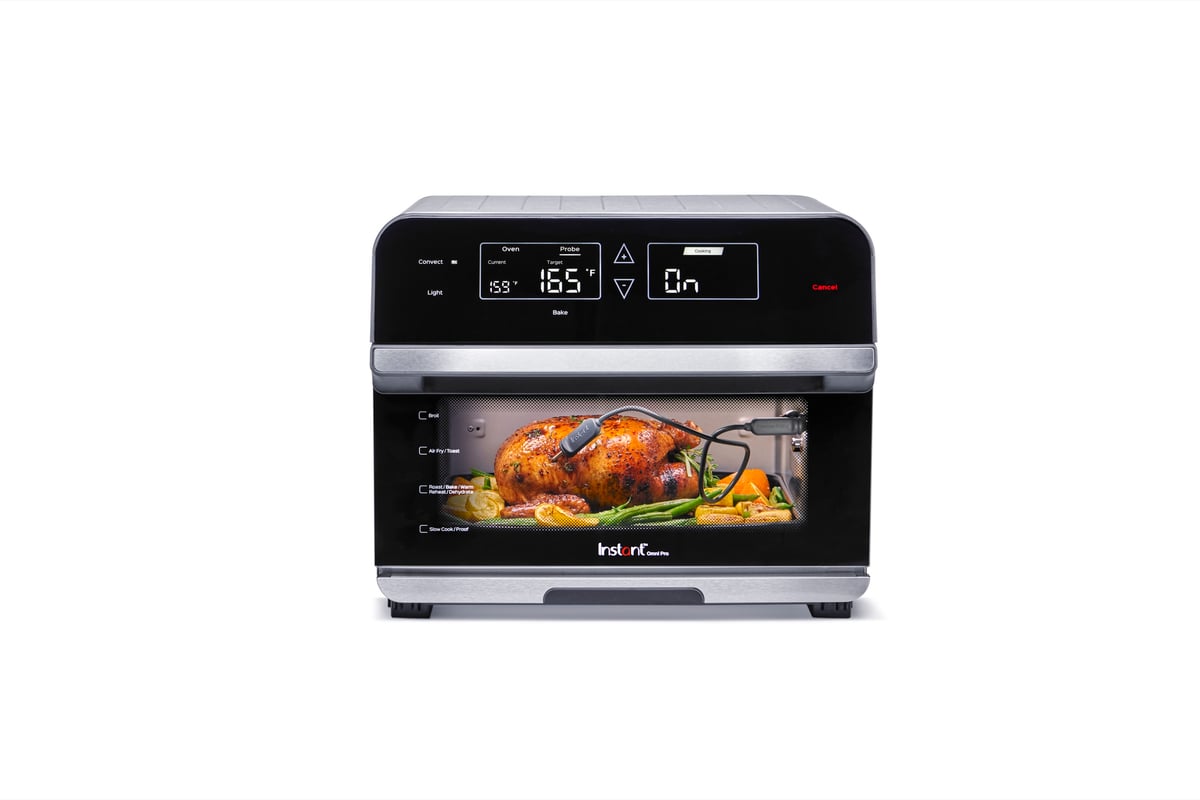 An Instant Pot air fryer oven with a whole roast chicken visible through the door, photographed on white