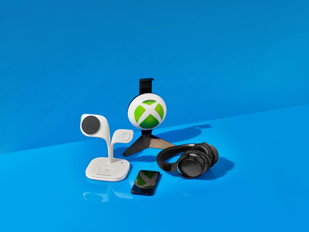 An Xbox controller, earbuds and gaming accessories arranged on a saturated blue ground