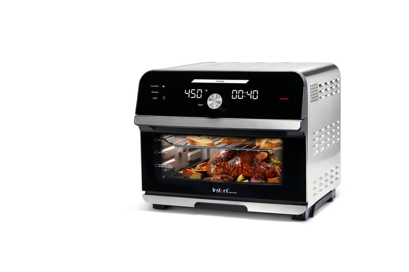 An Instant Pot air fryer oven with food browning inside, photographed on white