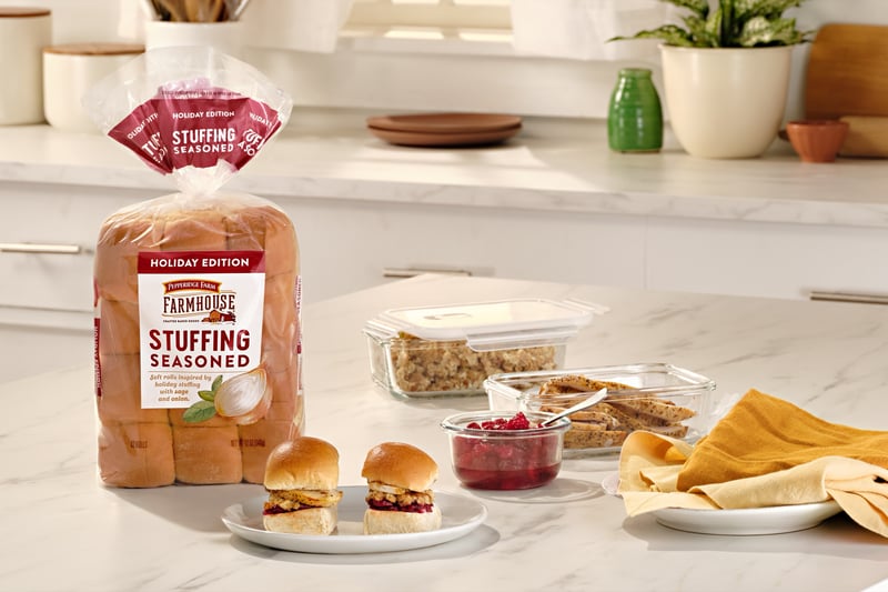 A kitchen counter laid with a bag of stuffing bread, dips, crackers and small sandwiches