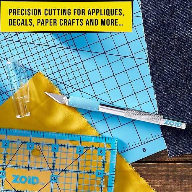 A craft knife and ruler on a blue self-healing cutting mat with yellow fabric and denim
