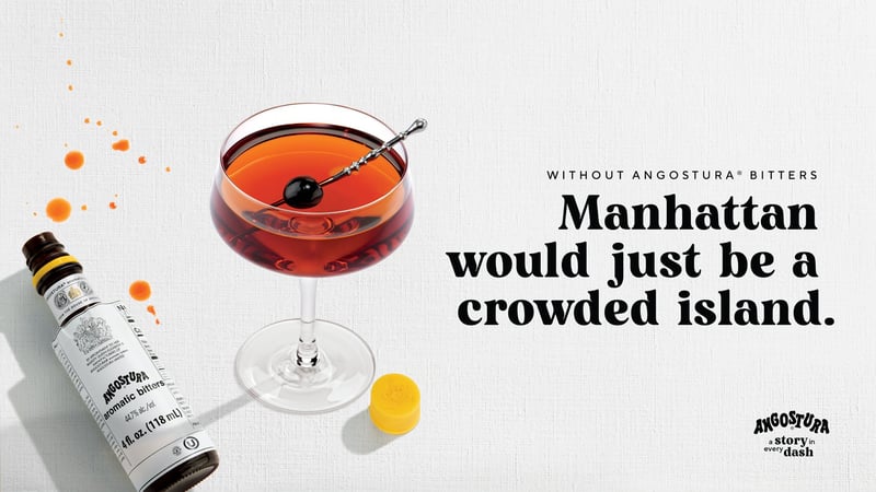 A Manhattan cocktail beside a bottle of Angostura bitters and a twist of lemon on textured paper