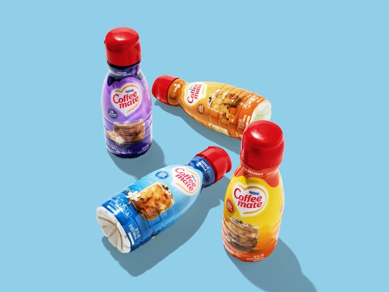 Coffee Mate creamer bottles arranged on a pale blue ground with hard shadows