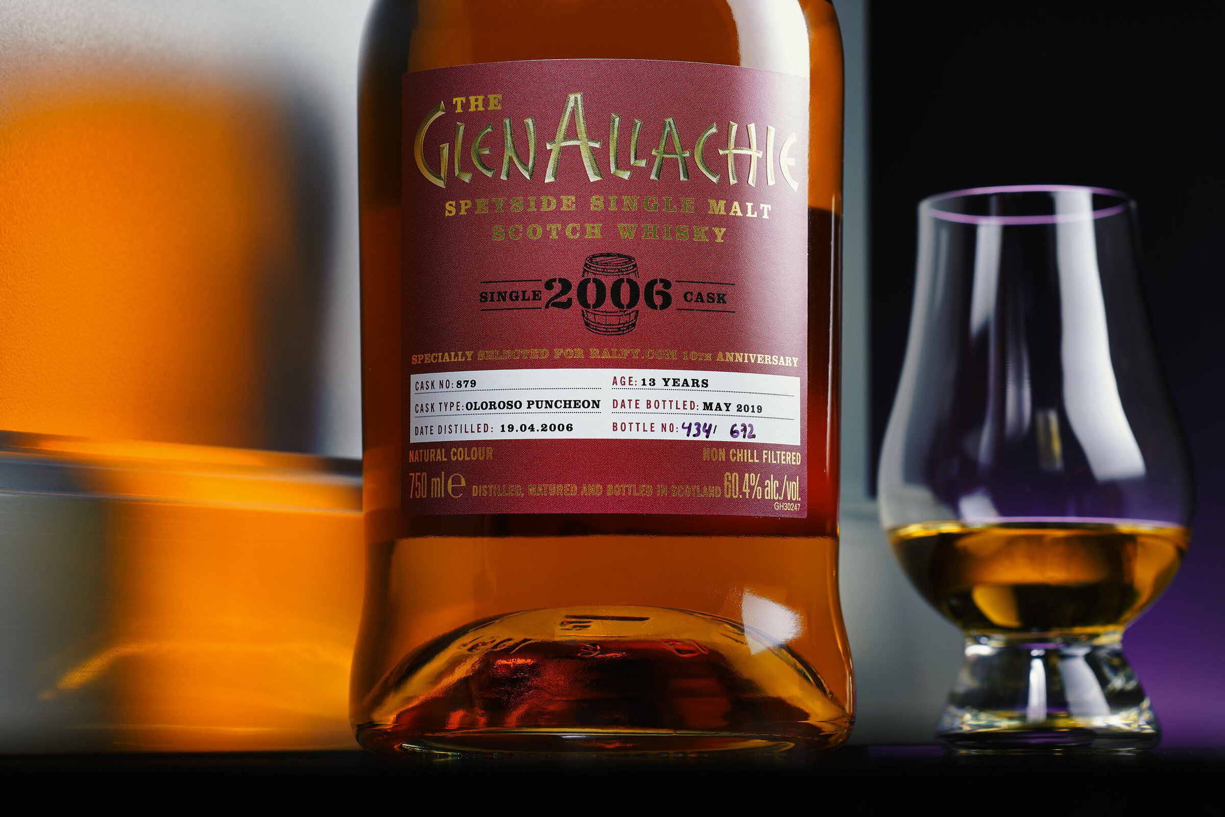 A GlenALLachie 2006 bottle beside a Glencairn glass, lit in warm amber against dark