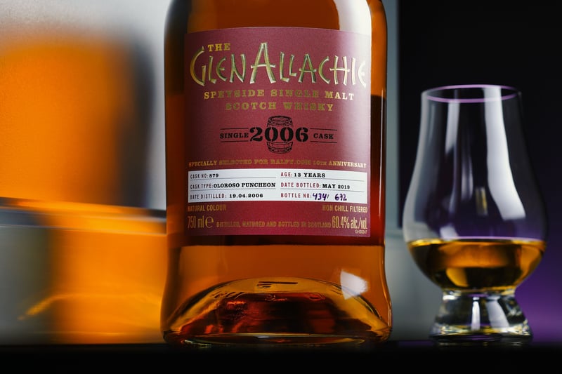 A GlenALLachie 2006 bottle beside a Glencairn glass, lit in warm amber against dark
