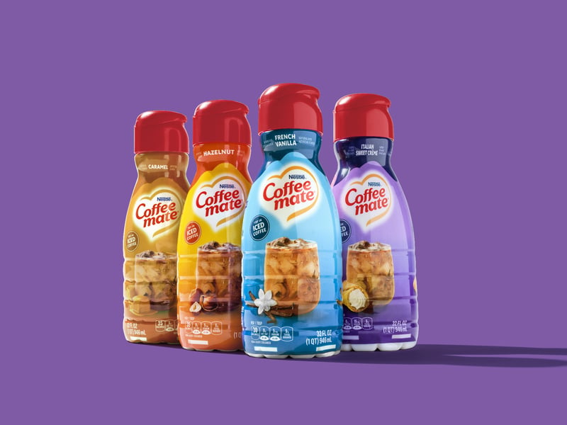 Four Coffee Mate creamer bottles grouped on a flat purple ground