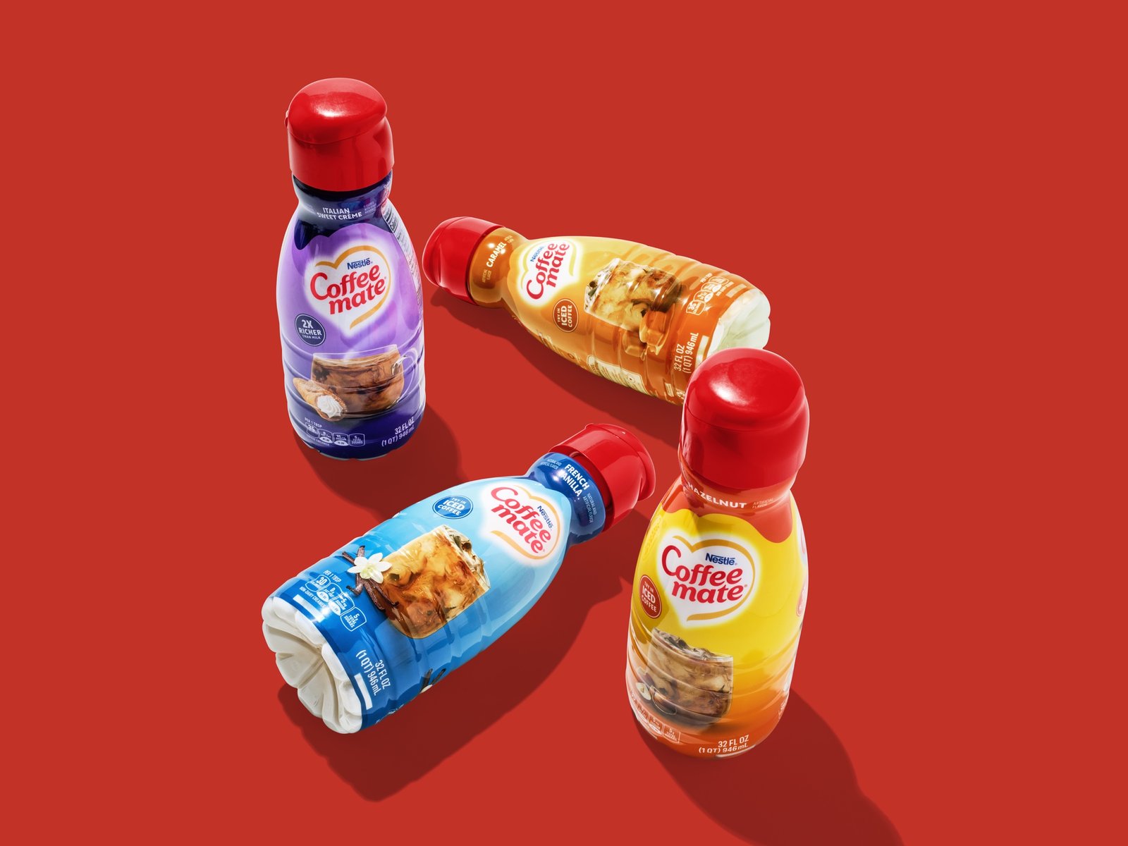 Coffee Mate creamer bottles tumbled across a flat red ground