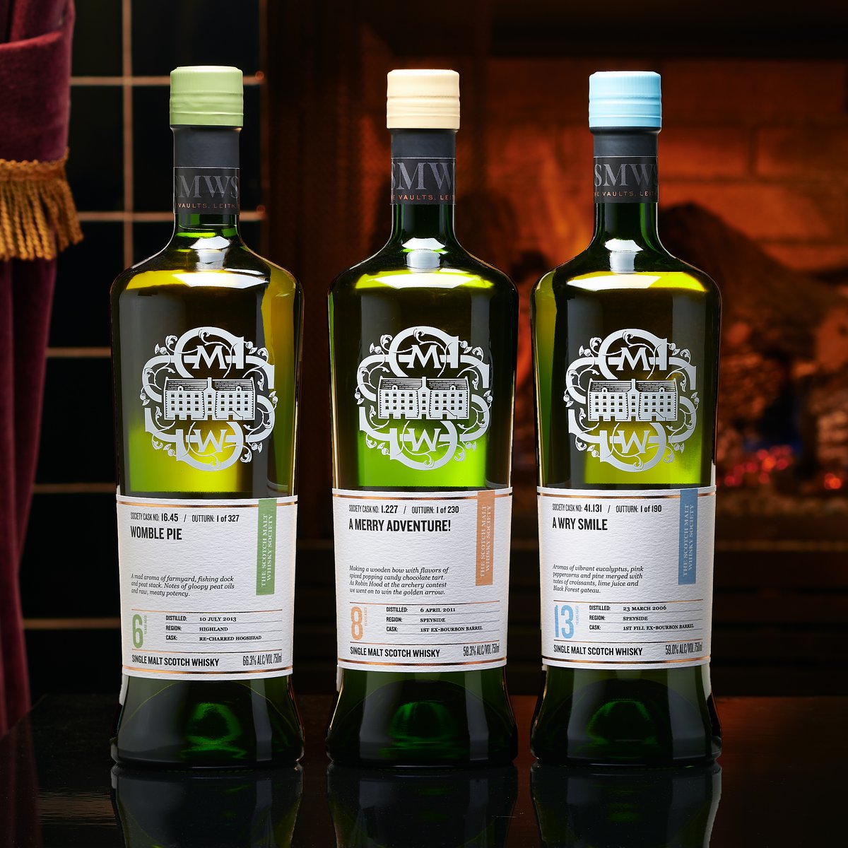 Three Scotch Malt Whisky Society bottles standing in a row in a warm, low-lit room