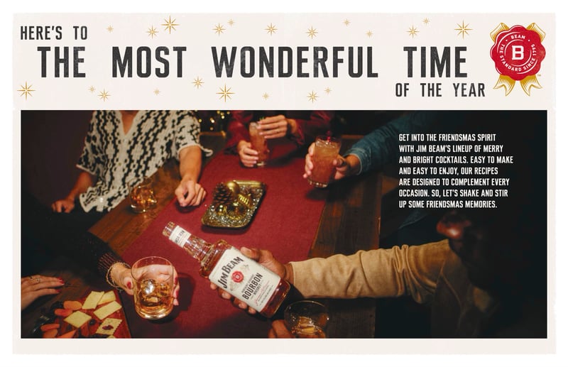 An overhead holiday scene of hands reaching across a red table set with bourbon glasses and snacks