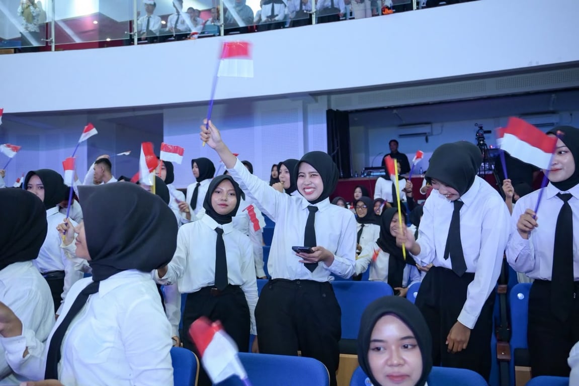 Lulusan SMK dan LKP berseragam putih hitam mengibarkan bendera Merah Putih kecil di kursi penonton