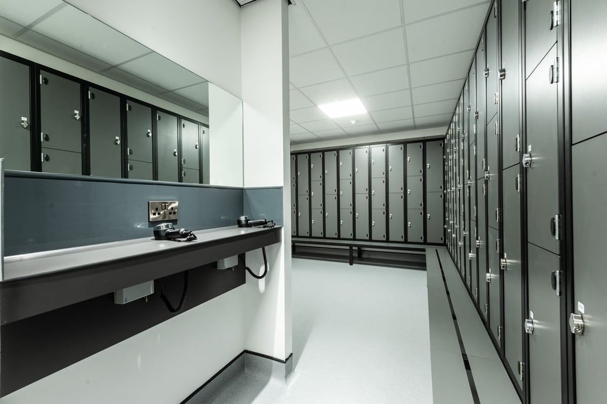 PureGym Macclesfield Silk Road: Rows of lockers, benches, in a gray utilitarian changing room setting.