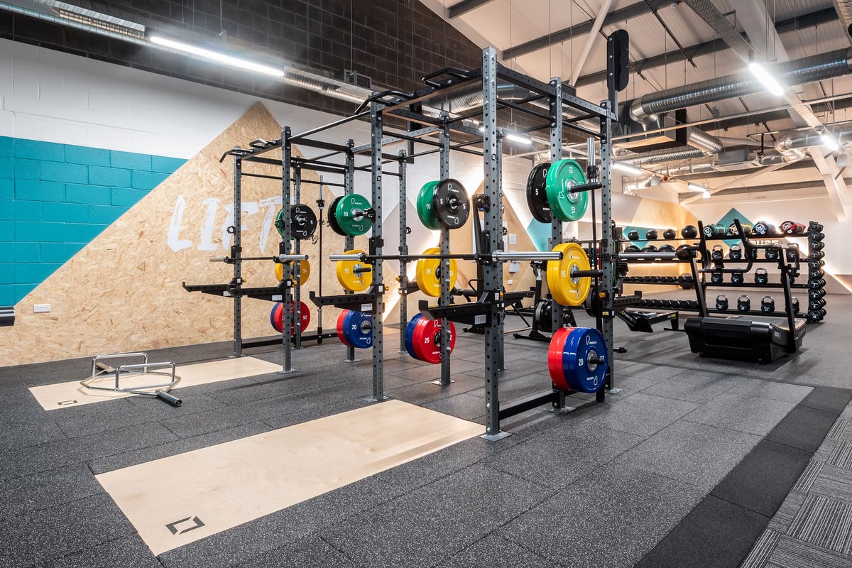PureGym Aberdare: Squat racks, weight plates in various colours, rubberized flooring, and weight racks.