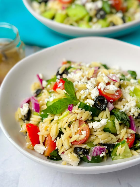 Orzo pasta salad with cherry tomatoes, black olives, cucumber, red onion, feta, and basil
