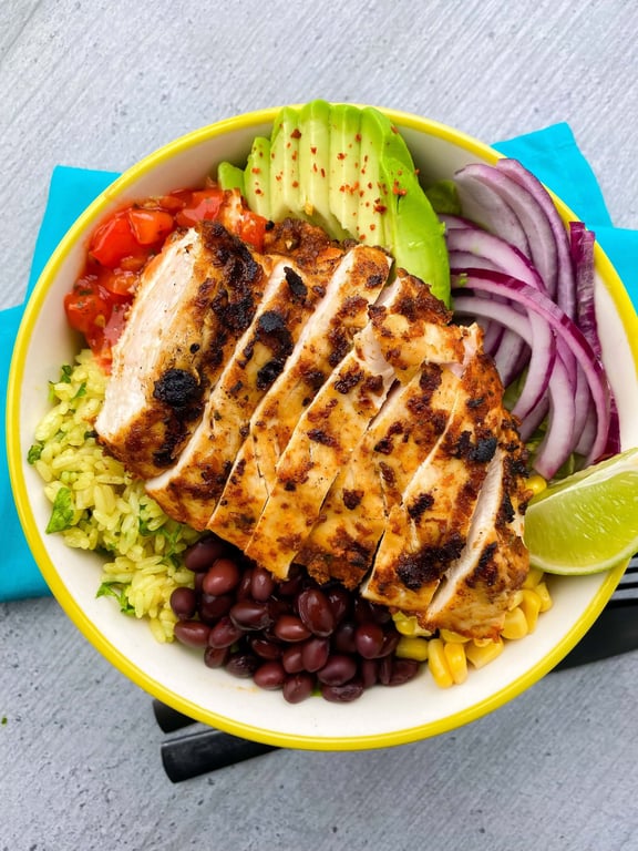Grilled chicken breast slices with avocado, black beans, corn, rice, red onion, salsa, and