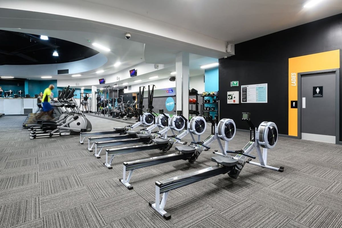 PureGym Northampton Central: Rows of stationary bikes, elliptical machines, and weight benches in a modern gym interior.