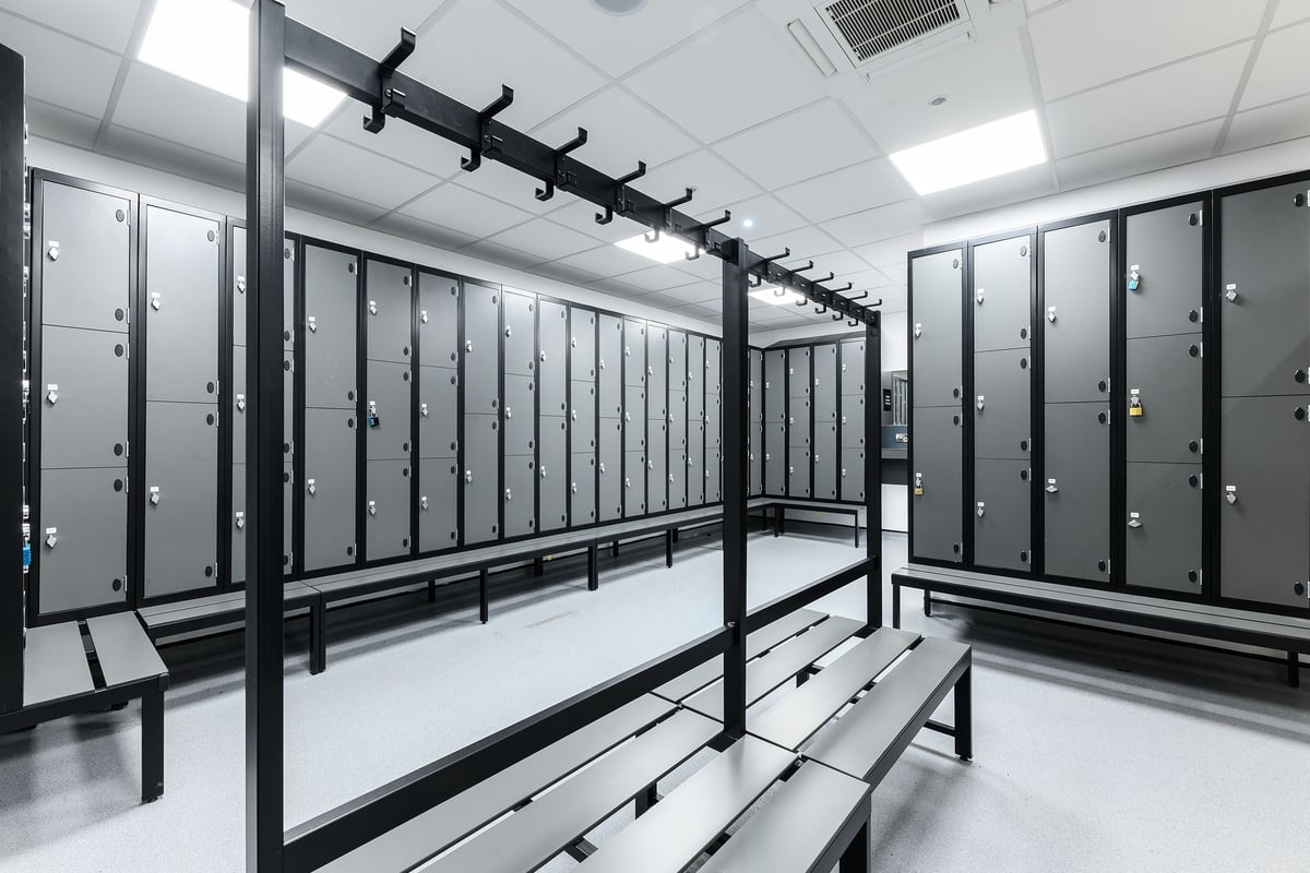 PureGym Wisbech: Rows of lockers, benches, and hanging rails in a changing room.
