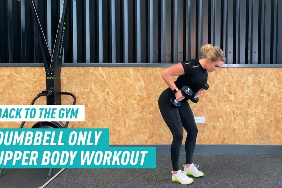 Woman in black workout clothes lifting dumbbells in gym with wooden wall background