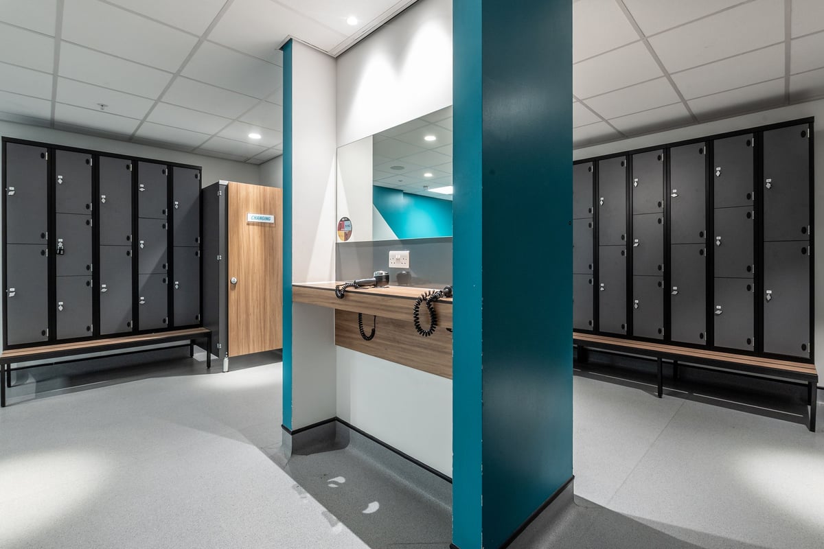 PureGym London Swiss Cottage: Rows of lockers, reception desk, and tiled floor--appears to be a changing area.