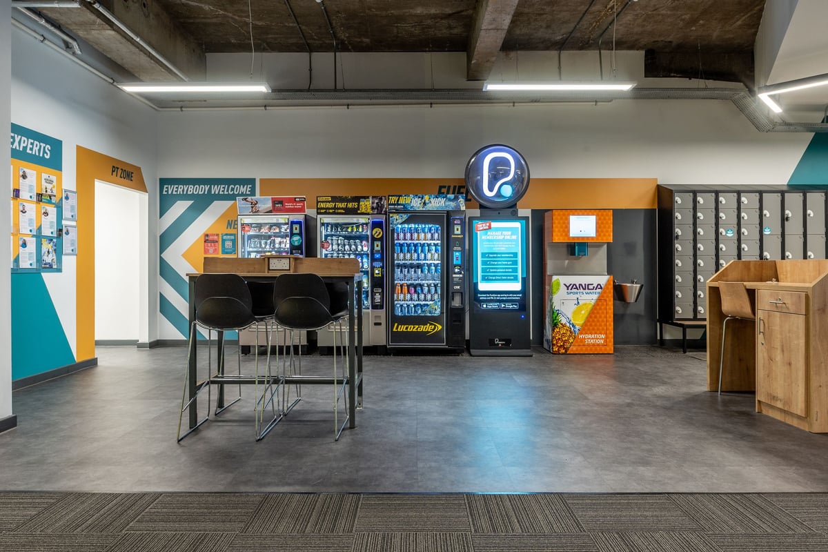 PureGym London Swiss Cottage: Vending machines, seating, signage, and vending area in a common space.