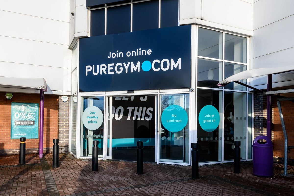 PureGym Aylesbury: Gym entrance with signage advertising online membership and circular floor decals.