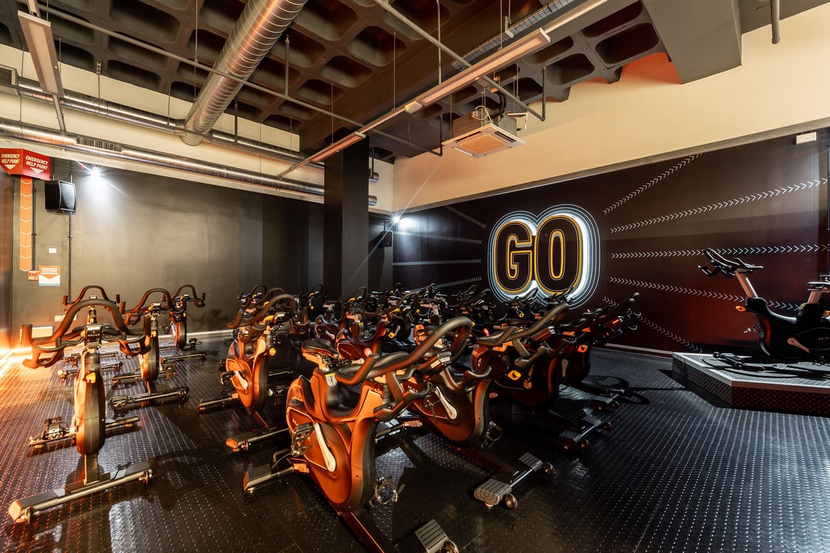 PureGym Ipswich Buttermarket: Rows of stationary bikes lined up facing large illuminated "GO" signage.