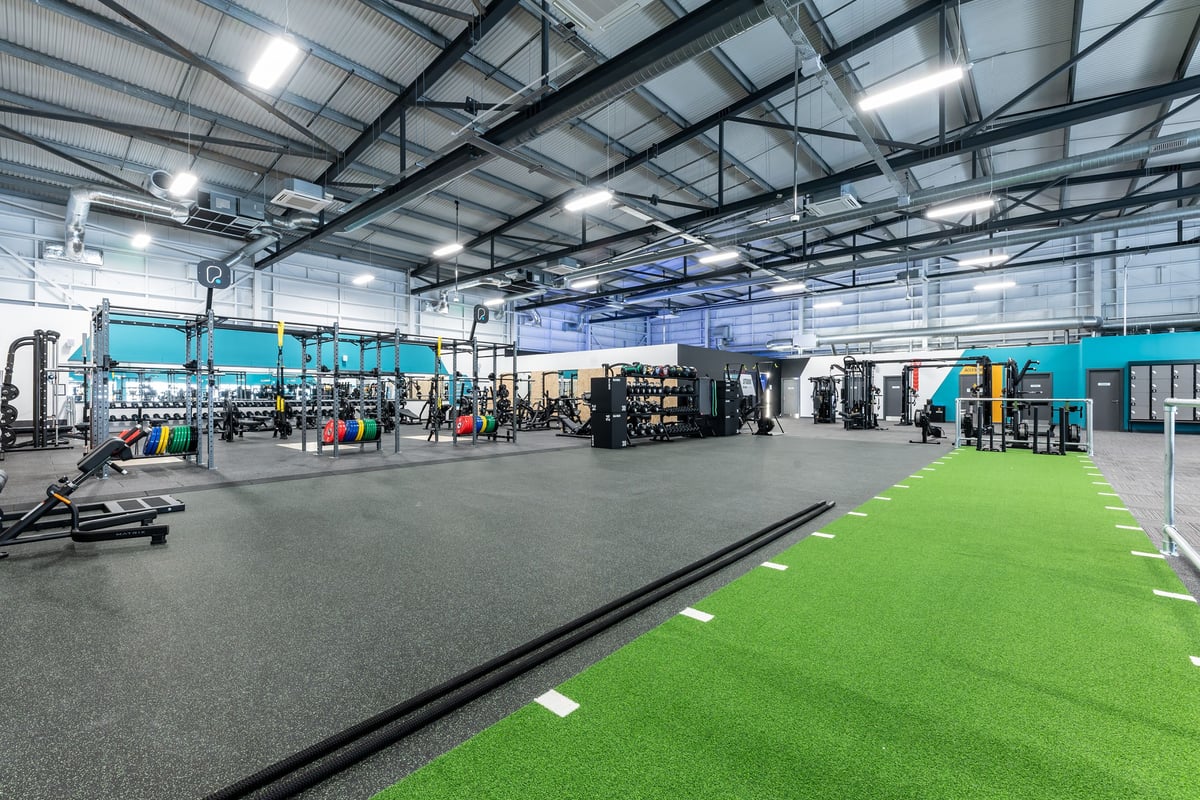 PureGym Ipswich Ravenswood: Weightlifting area with squat racks, resistance machines, free weights, green turf section.