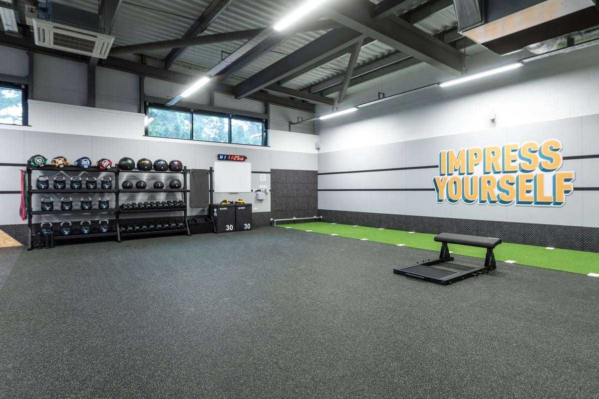 PureGym Plymouth Derriford: Rows of resistance machines, benches, green turf area, and motivational wall graphics.
