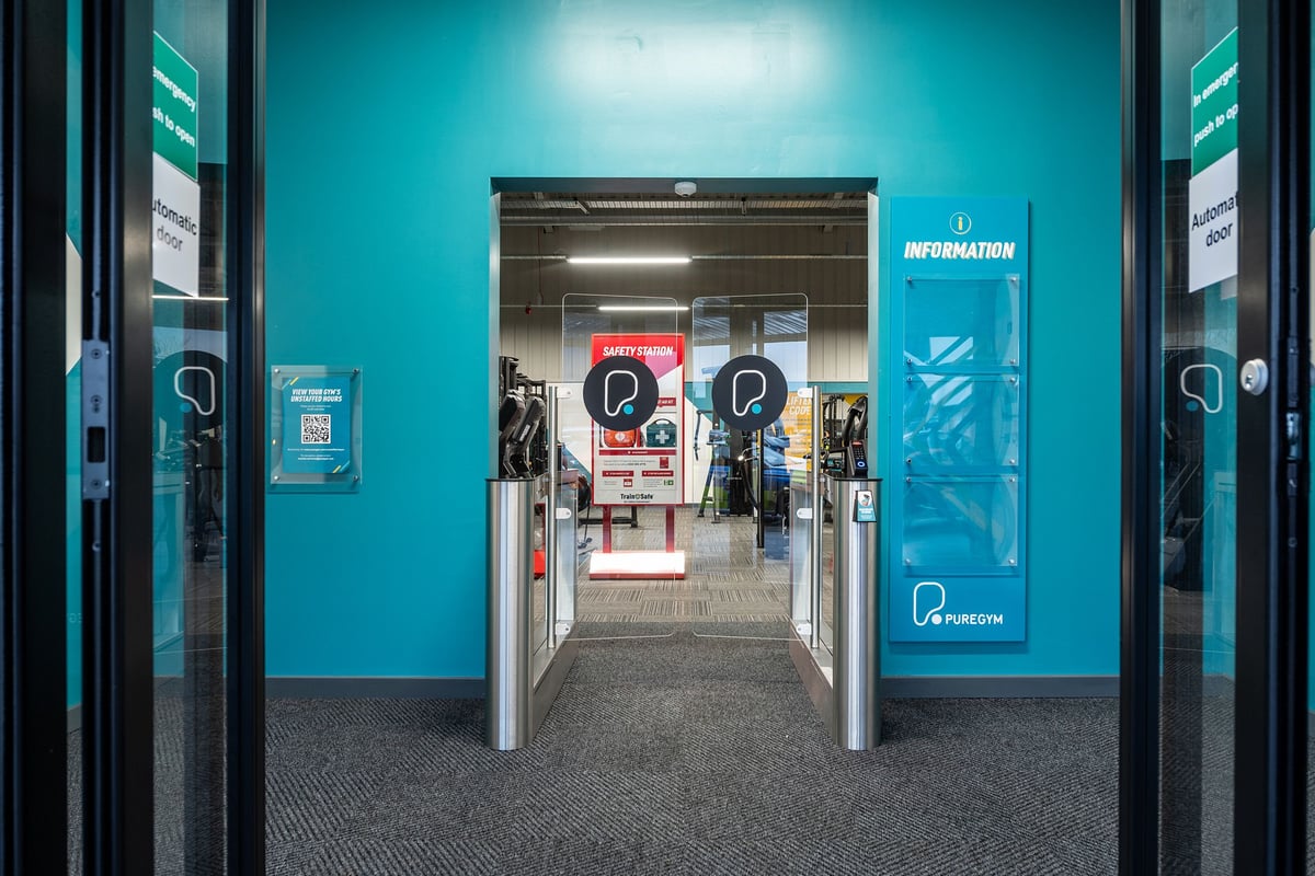PureGym Alfreton: The entrance area of a building with information kiosks and turnstiles.