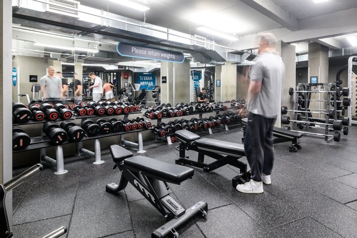 PureGym London Lewisham: Weight racks, dumbbells, benches, rubberised flooring in a gym area.