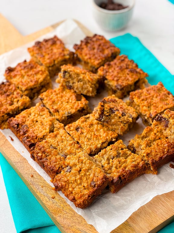 Golden baked oat and chocolate chip bars cut into squares on parchment paper