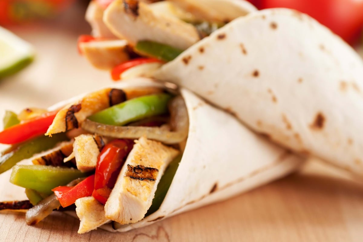 Grilled chicken fajitas with red and green peppers wrapped in a flour tortilla