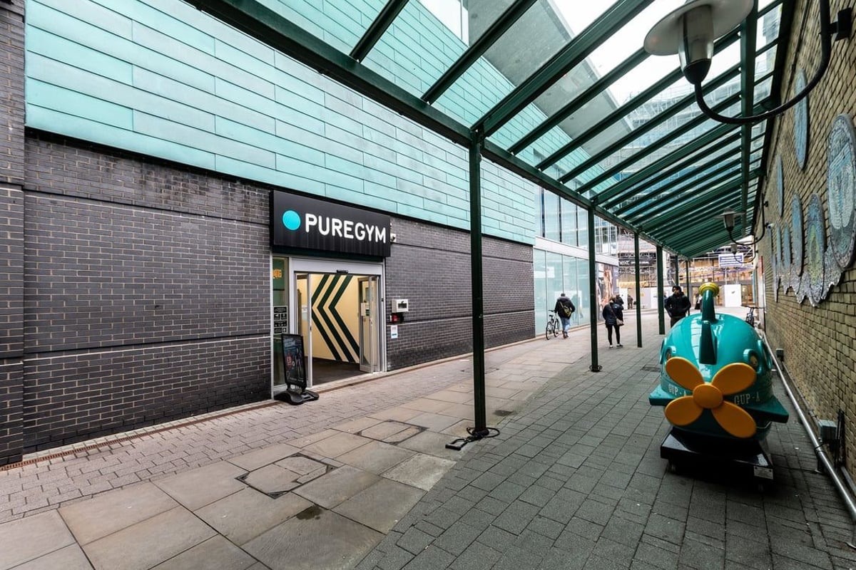 PureGym Walton-on-thames: Exterior walkway with Pure Gym signage, glass canopy, and bike sculpture.
