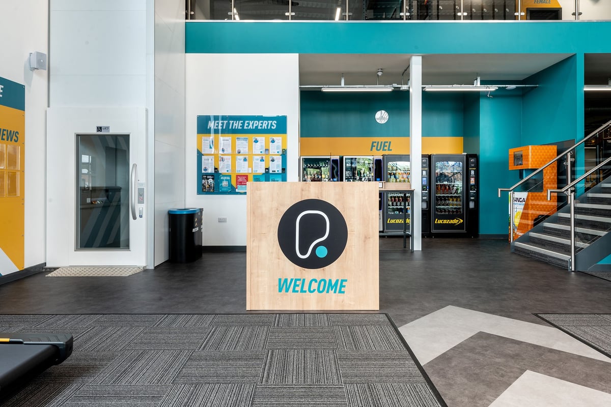 PureGym Nottingham West Bridgford: Entrance area with vending machines, welcome signage, and seating.