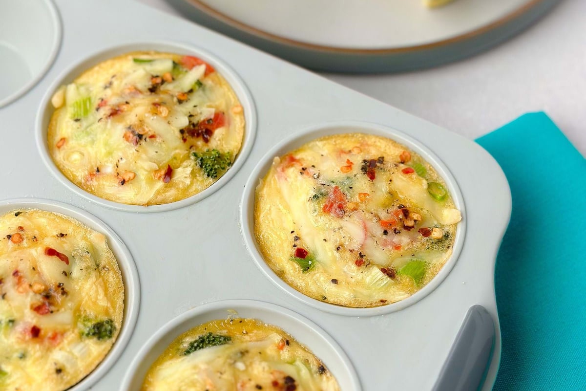 Mini vegetable frittatas with cheese and red pepper flakes in a baking tray and on a plate