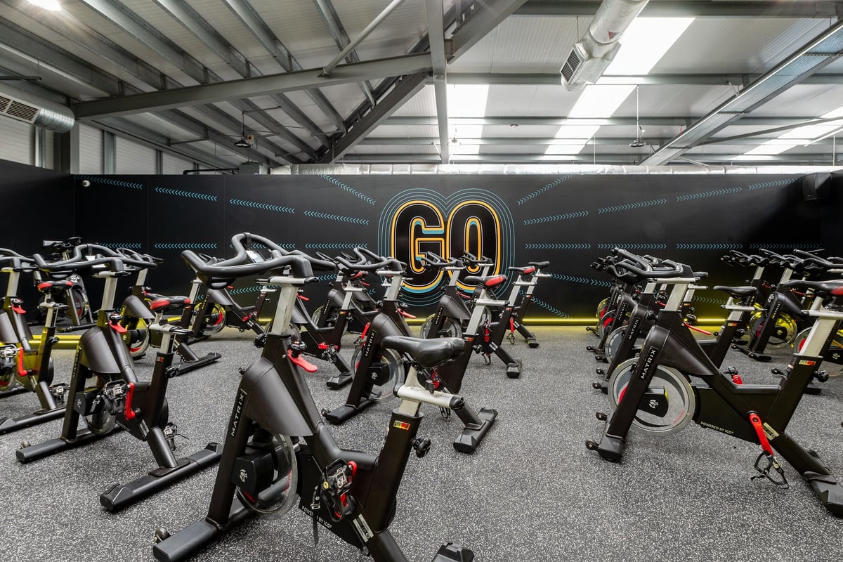 PureGym Coventry Warwickshire Shopping Park: Rows of stationary spinning bikes in a studio with large 'GO' lettering.