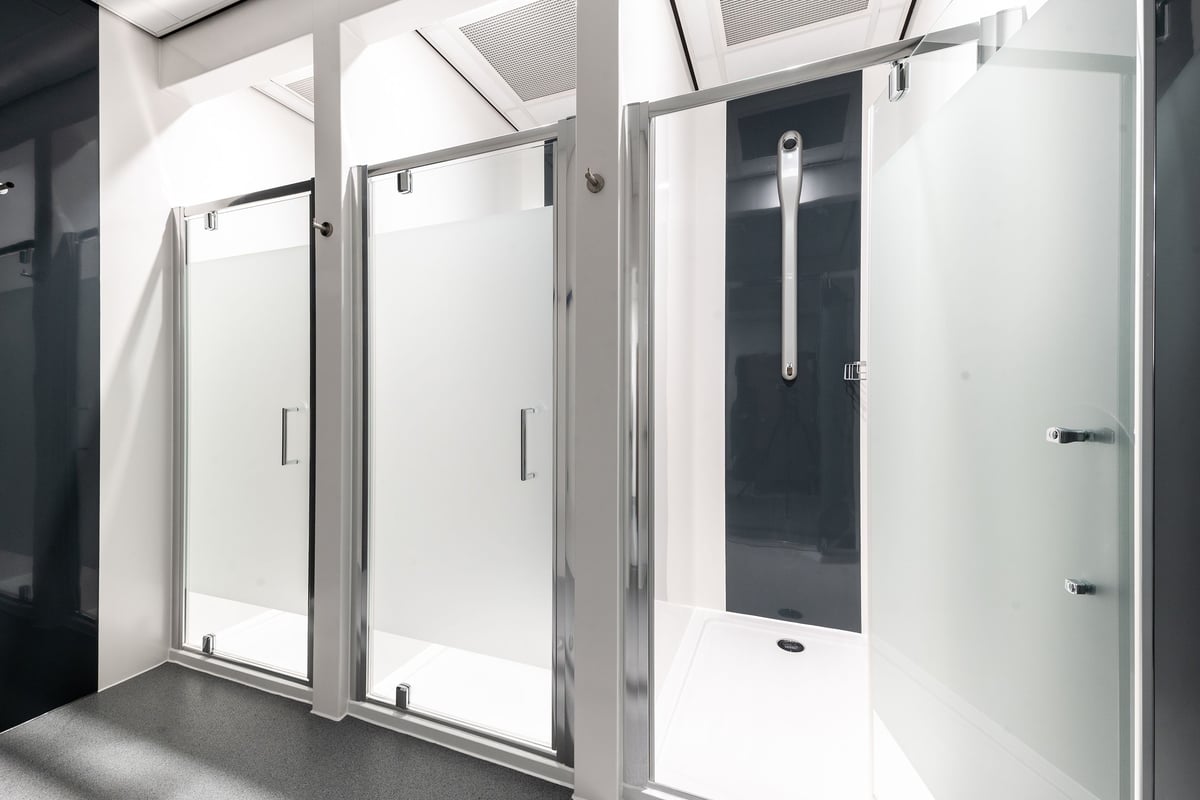 PureGym Barnsley: Rows of enclosed shower cubicles with glass doors and chrome handles.