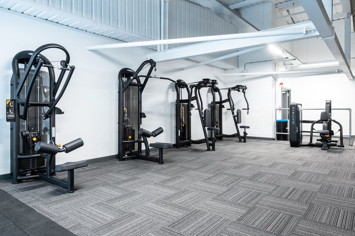 PureGym Cheshunt Brookfield Shopping Park: Resistance machines, benches, and patterned rubberized flooring in a gym facility.