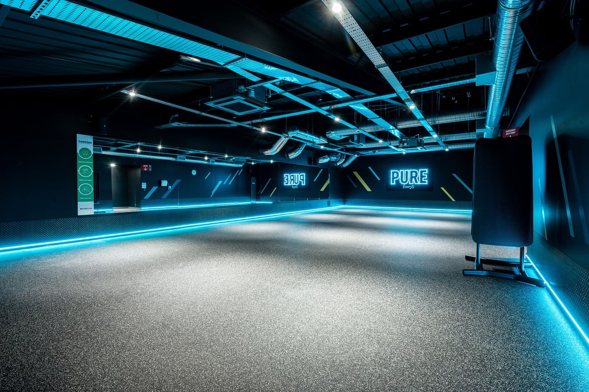 PureGym Yeovil Houndstone Retail Park: Futuristic studio with tubing, neon lighting, and rubberized flooring.