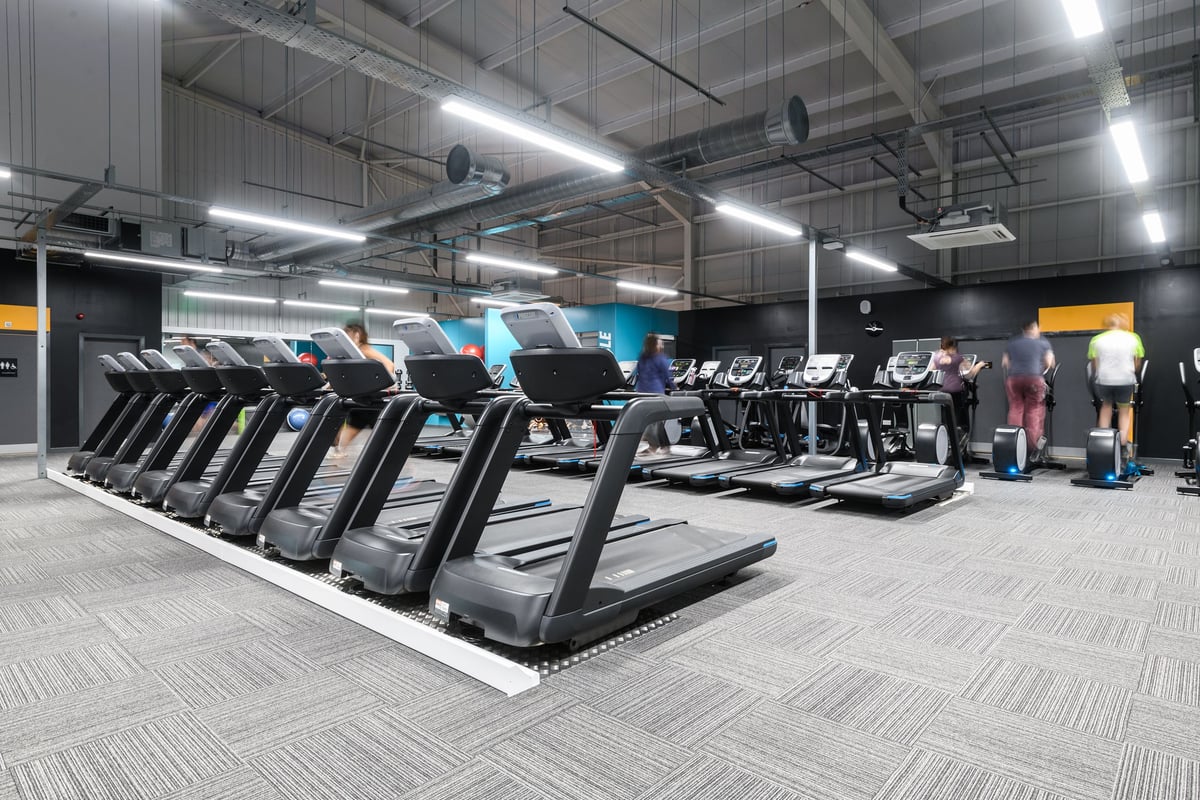 PureGym Nottingham Castle Marina: Rows of treadmills in a brightly lit gym with industrial-style ceiling and flooring.