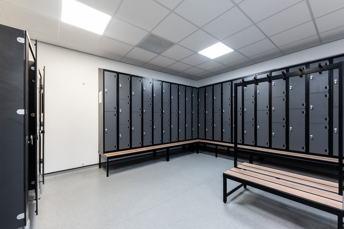 PureGym Gloucester Retail Park: Locker room with benches and rows of lockers lining the walls.