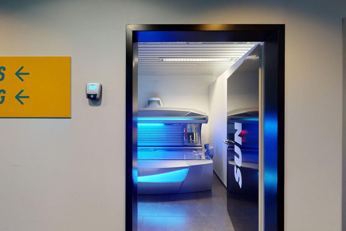PureGym Kriens: Brightly-lit entry gate with futuristic blue lighting, showing an inviting fitness studio interior.
