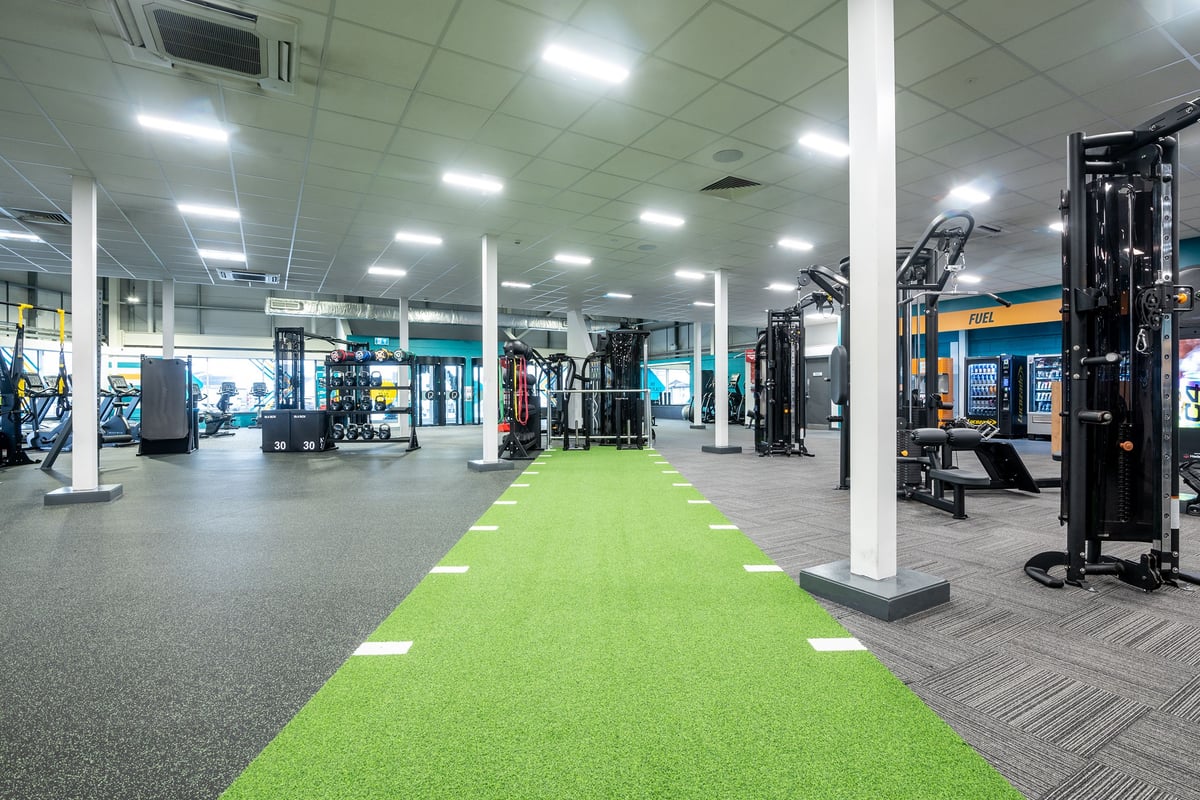 PureGym Aberdeen Kittybrewster: Gym floor with resistance machines, green turf area, free weights, and rubberized flooring.