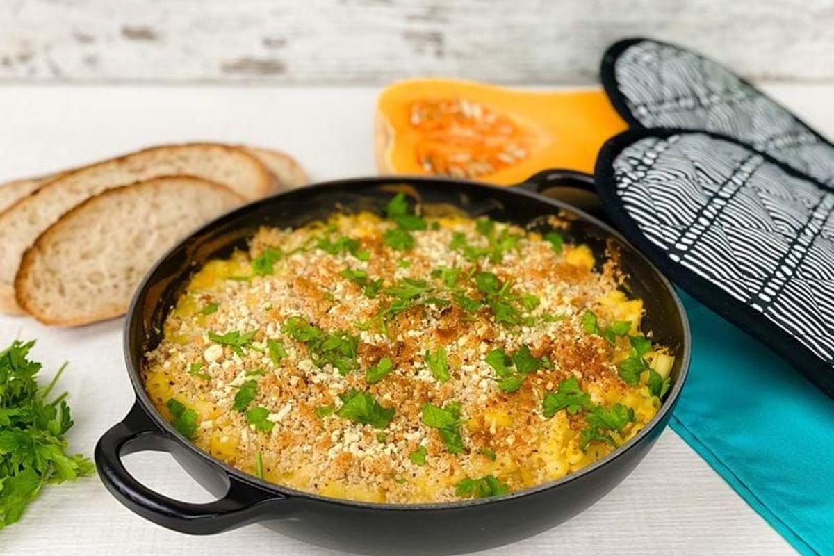 Baked macaroni and cheese topped with breadcrumbs and parsley in a black pan