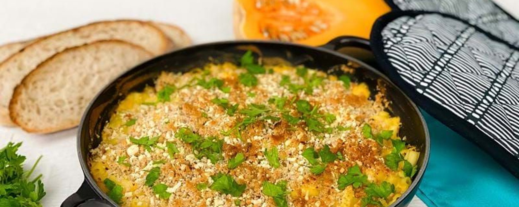 Baked macaroni and cheese topped with breadcrumbs and parsley in a black pan