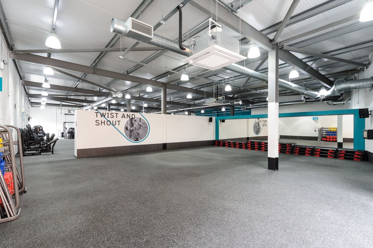 PureGym Leeds Regent Street: Gym interior with rubberized flooring, weight racks, free weights, and mirrors along the walls.