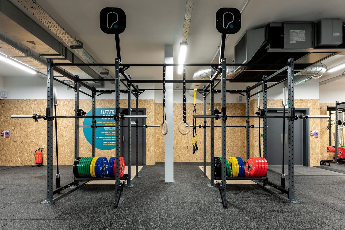 PureGym Boston: Weightlifting rig frames, rubberized floors, exposed brickwork, wall-mounted rigs for exercises.