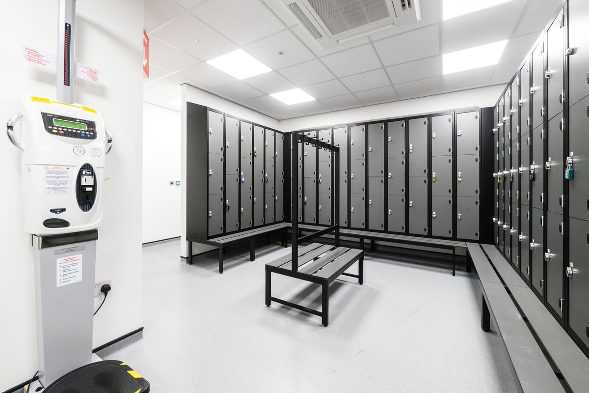 PureGym Cardiff Bay: Locker room with rows of lockers, benches, and numeric entry panel.