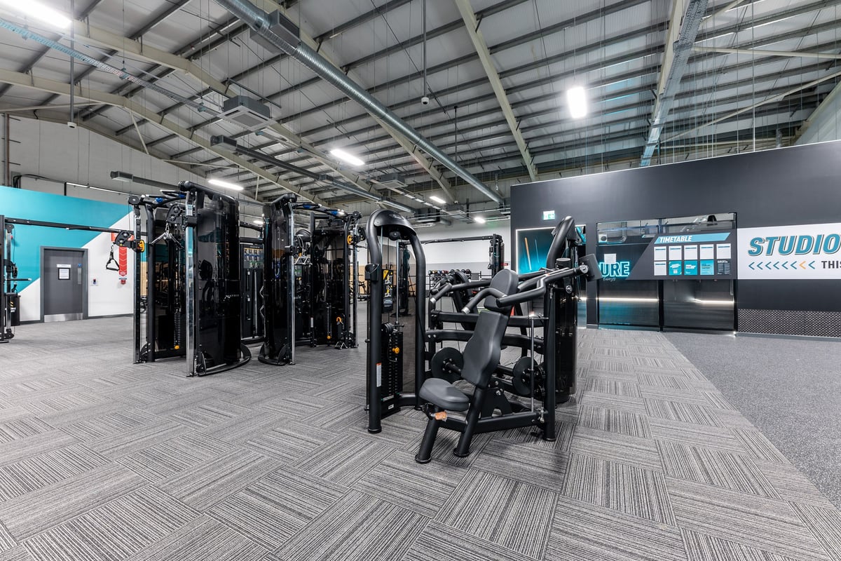PureGym Lincoln Carlton Centre: Weights room with resistance machines, free weights, mirrors, and rubberized flooring.