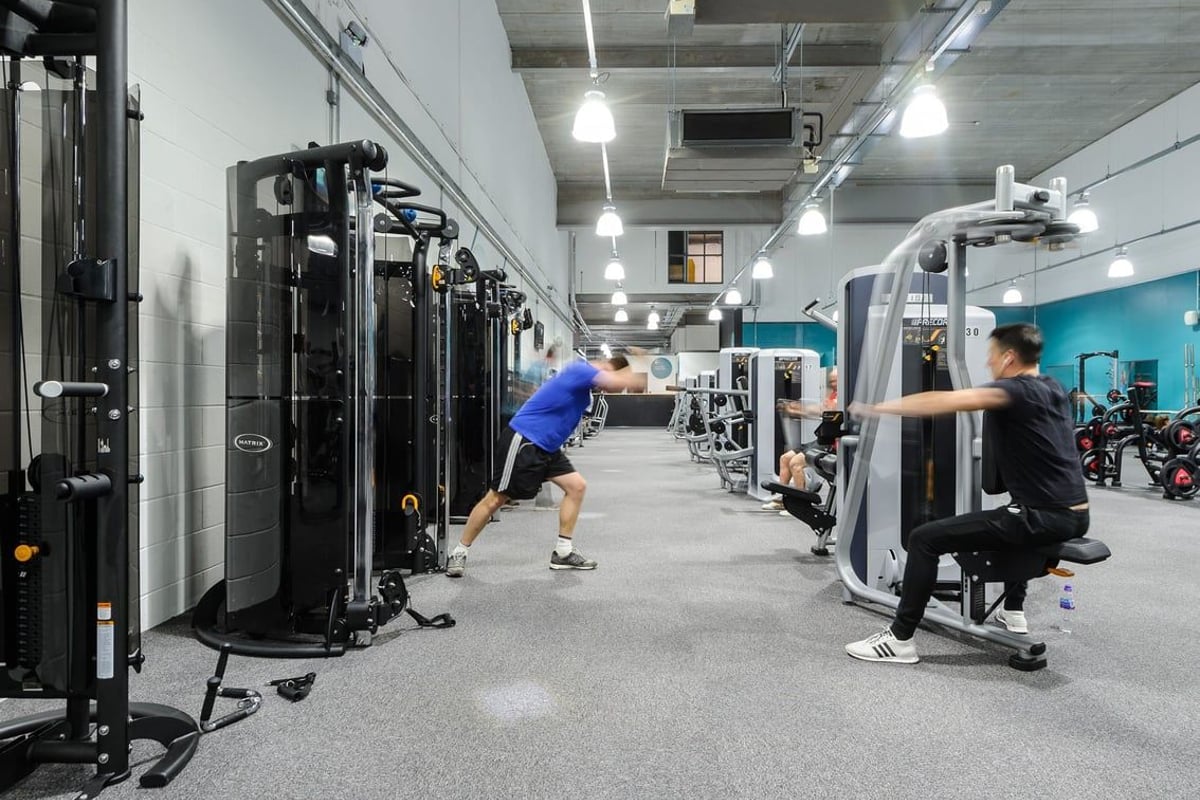 PureGym Bury: Rows of resistance machines, free weights, benches, and rubberized flooring in a brightly lit gym interior.