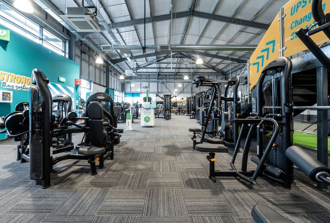 PureGym Cirencester: Rows of resistance machines, free weights, benches, and circuit equipment in a brightly lit gym.